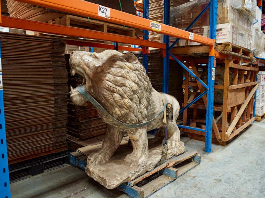 A large lion sculpture is stored securely in a professional Kent storage warehouse facility.