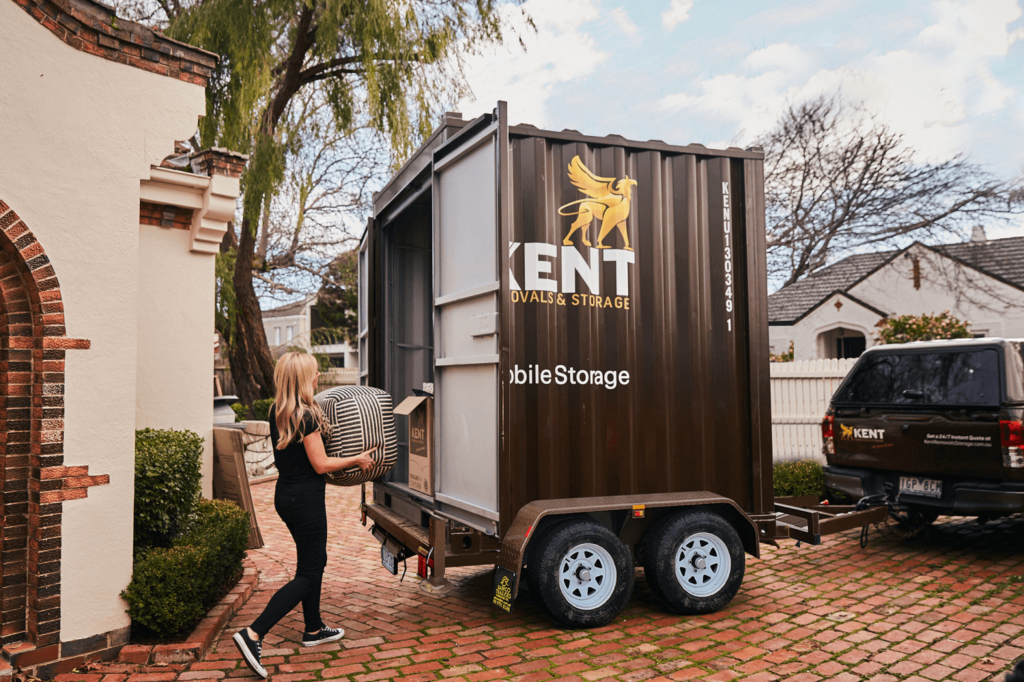 A young woman carries her striped ottoman into a Kent Storage portable mobile unit for flexible secure storage with Kent Removals & Storage.