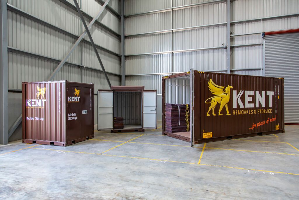Three Kent Storage storage solution containers sit in a Kent Storage warehouse facility.
